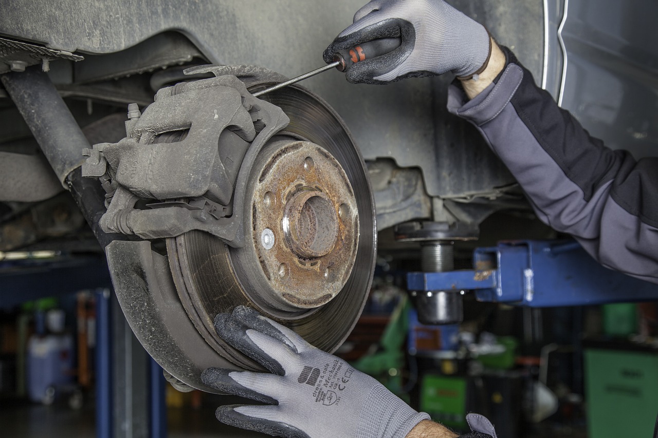 Image of gloved hands working on a car's disk brake system