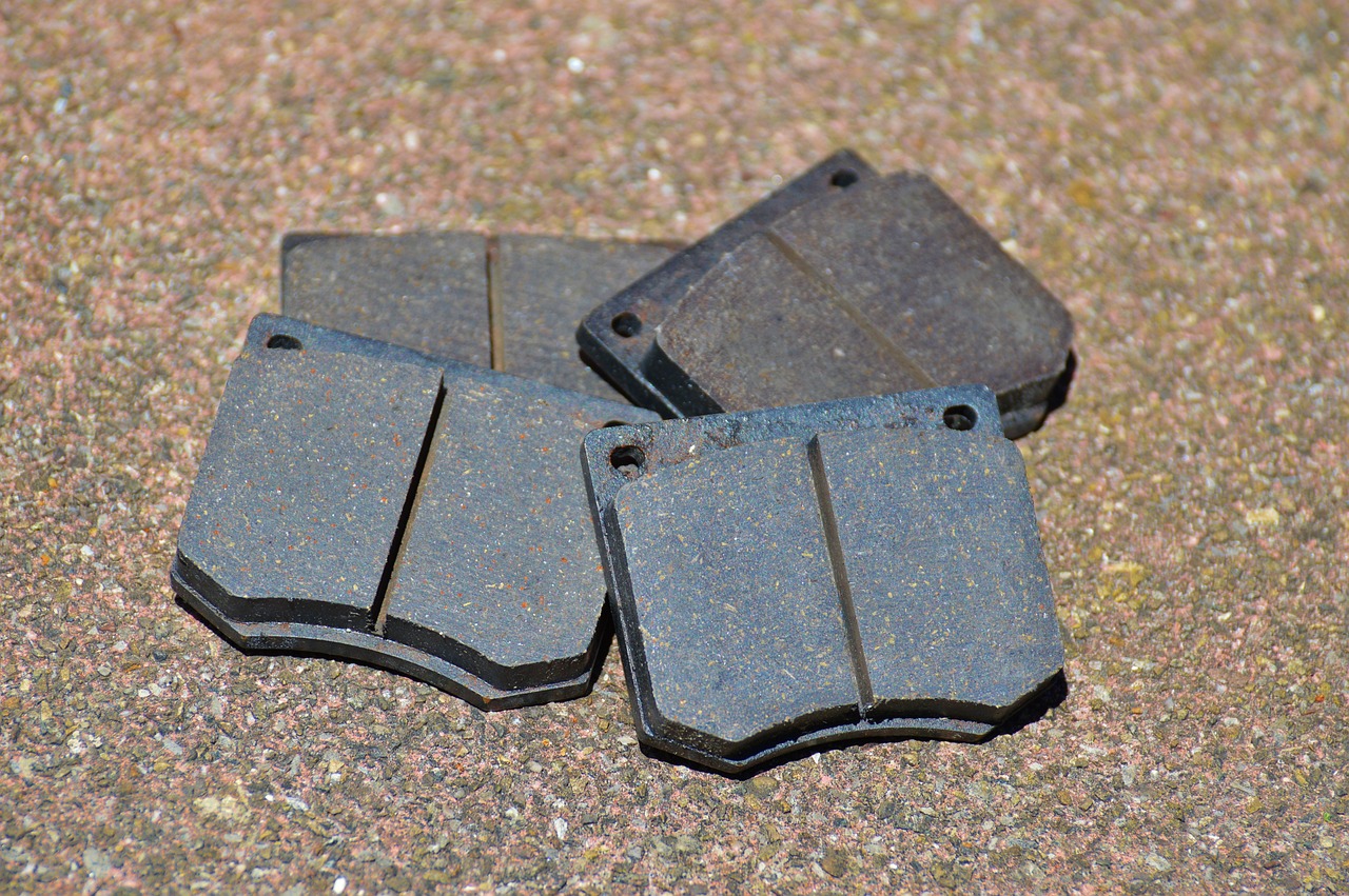 Four brake pads in a pile on a textured surface