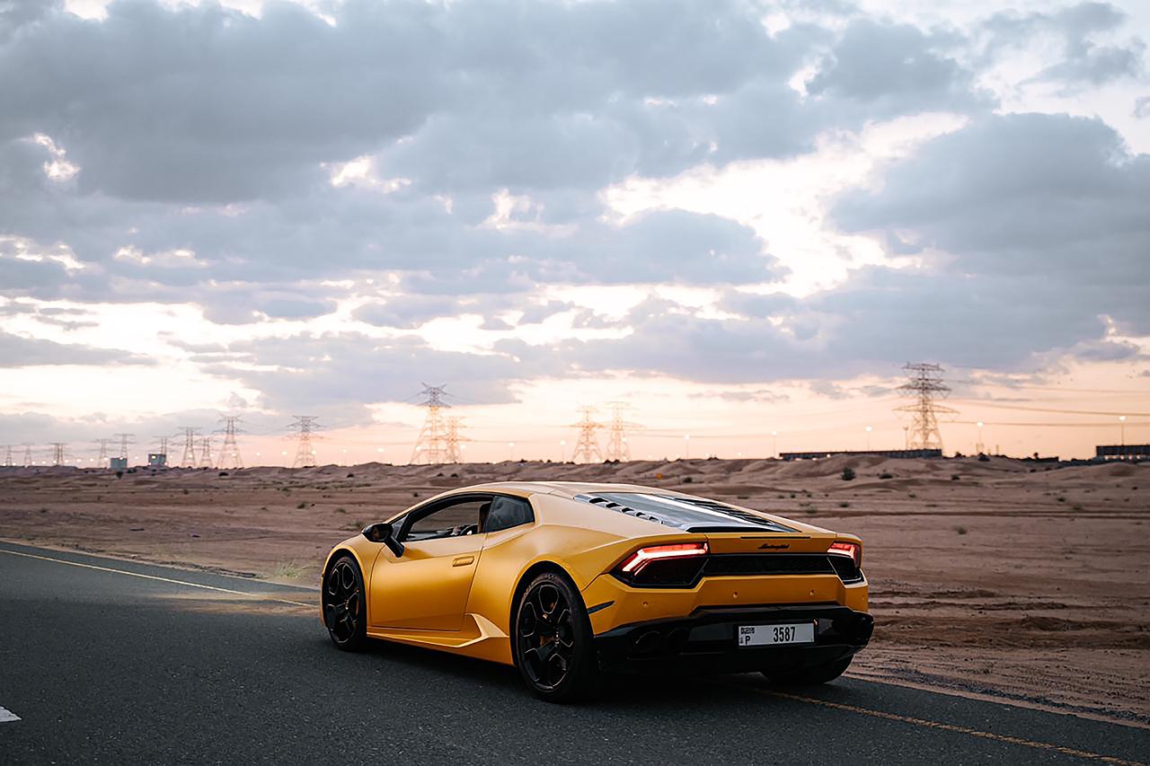 Orange sports car in front of bleak landscape at sunset